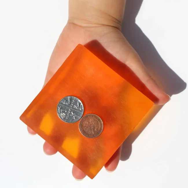 A little girl's hand holding a single bar of Dordana's unwrapped Mandarin Fresh soap.