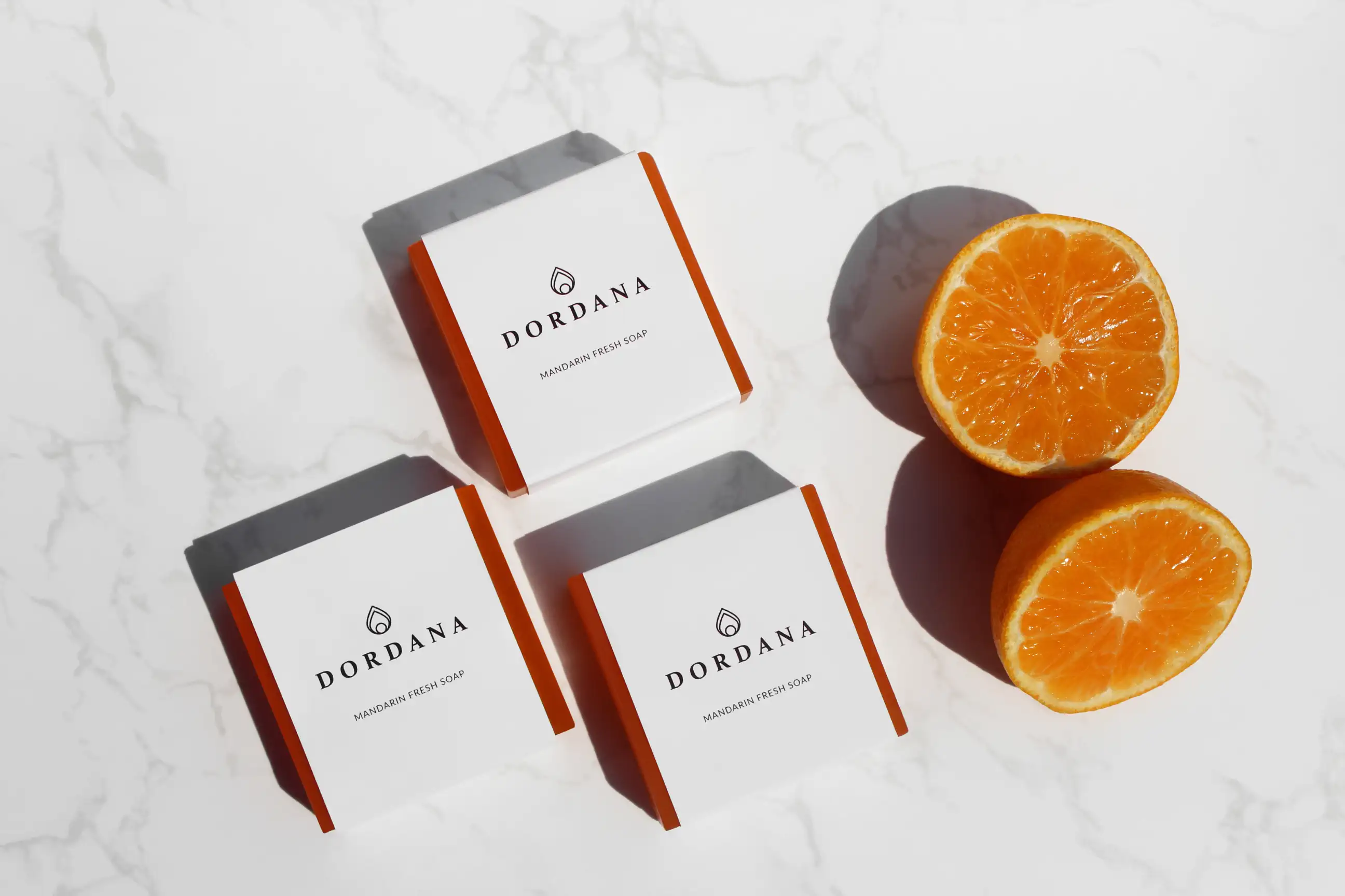 Wrapped bars of Dordana's Mandarin Fresh soap accompanied by succulent mandarins.