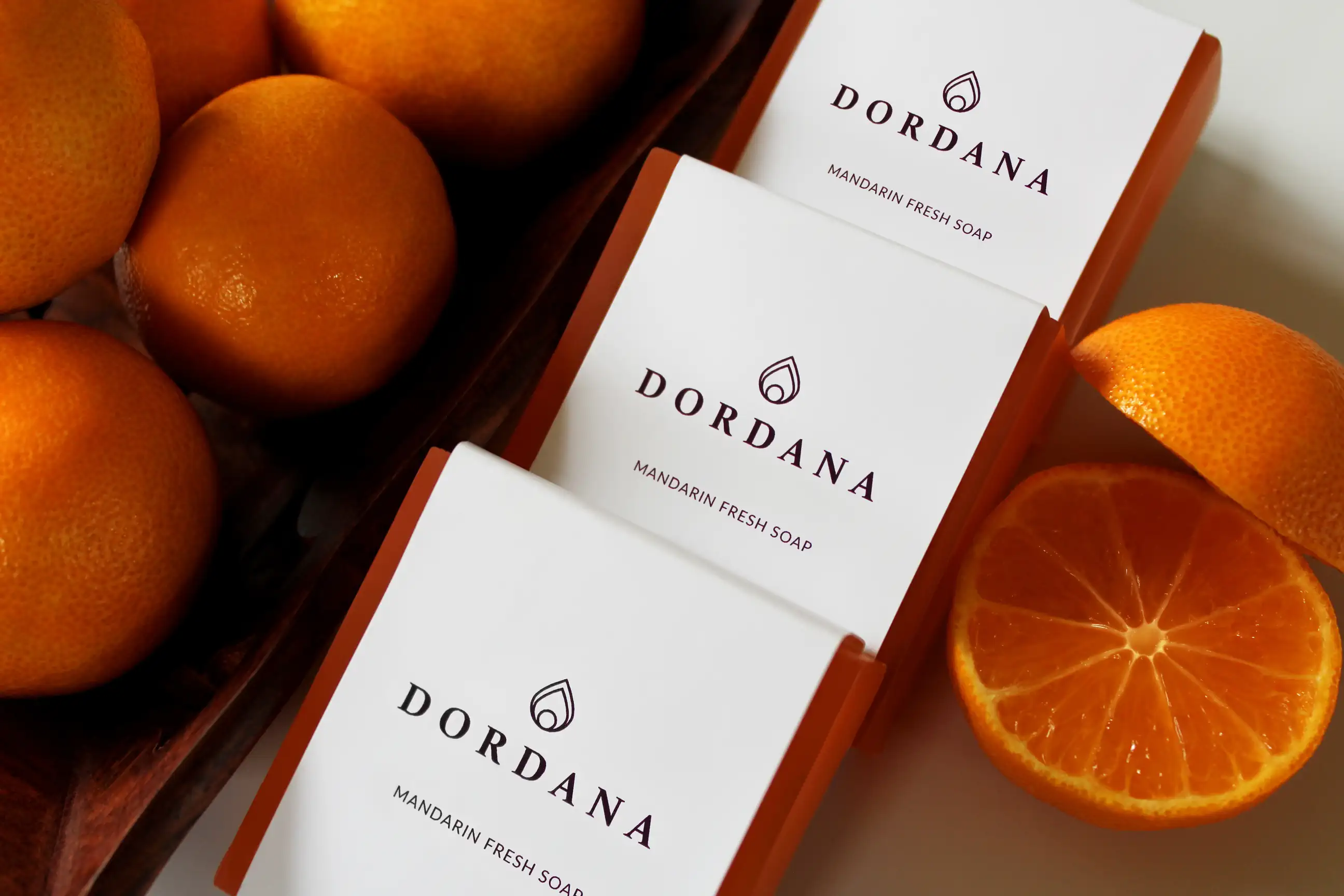 Wrapped bars of Dordana's Mandarin Fresh soap accompanied by succulent mandarins.